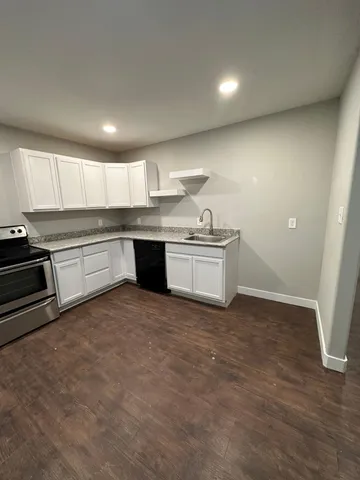 a kitchen with kitchen island granite countertop a sink and a stove top oven