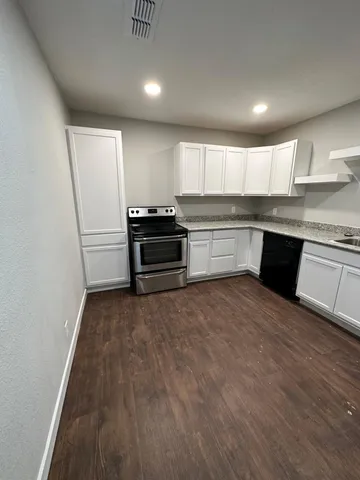 a kitchen with granite countertop a refrigerator and a stove top oven