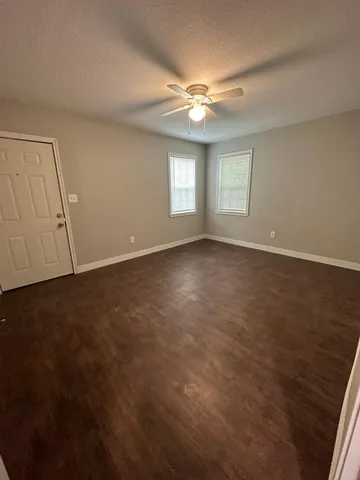 an empty room with a ceiling fan and window