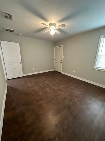 an empty room with window and chandelier fan