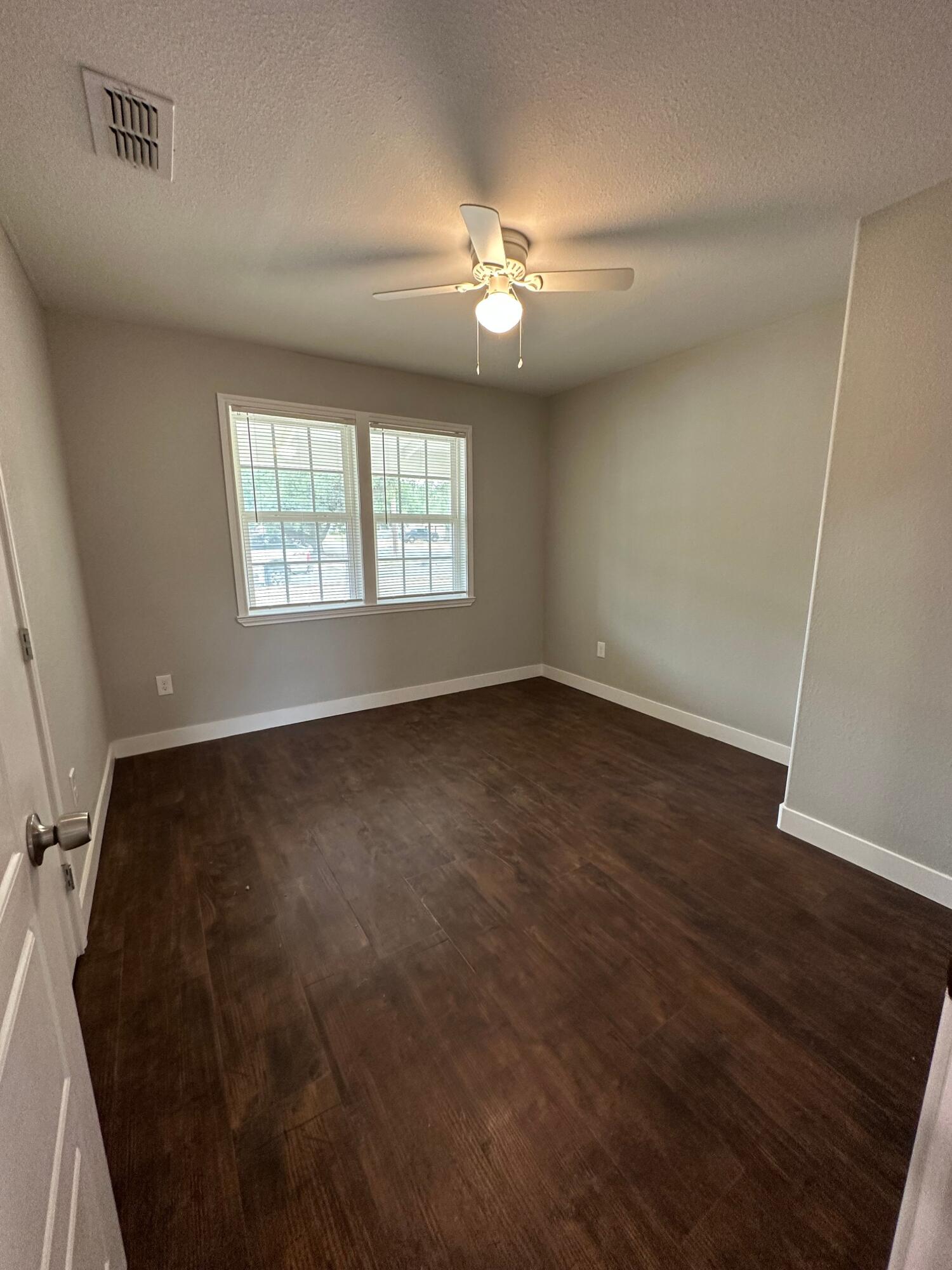 2824 35th Street, Unit A Lubbock, TX 79413 - Photo 10 of 16 an empty room with wooden floor fan and windows
