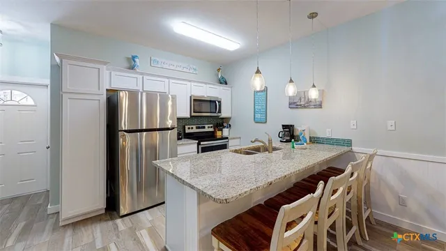 a kitchen with granite countertop a refrigerator a stove a microwave and island