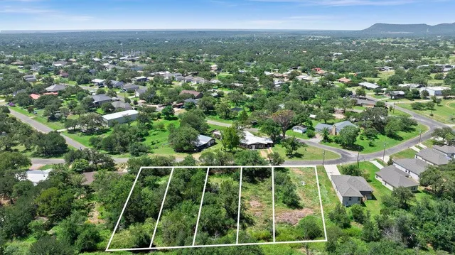a view of a green field with a houses in the background