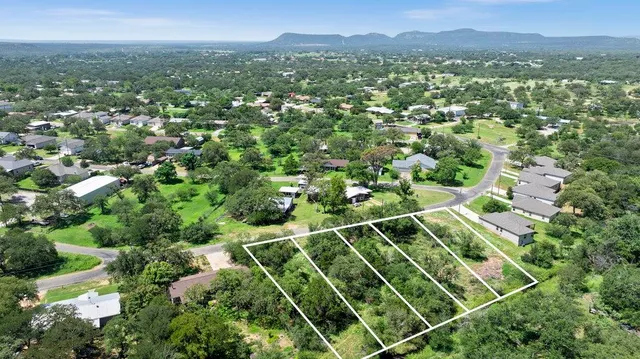an aerial view of residential houses with outdoor space and trees