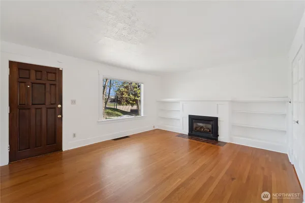 an empty room with wooden floor cabinet and windows