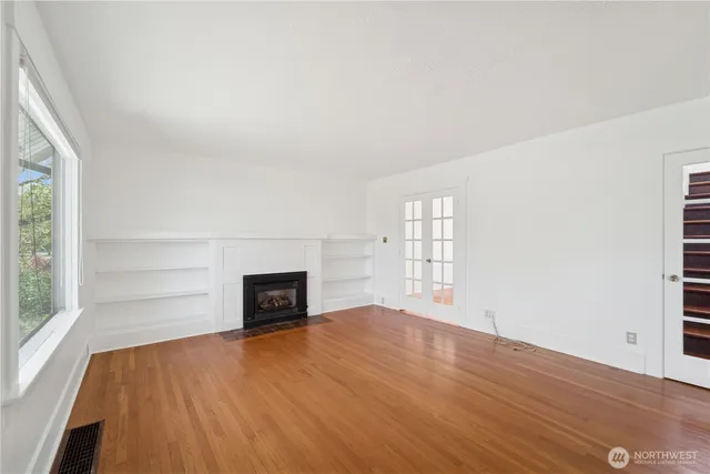 an empty room with windows and fireplace