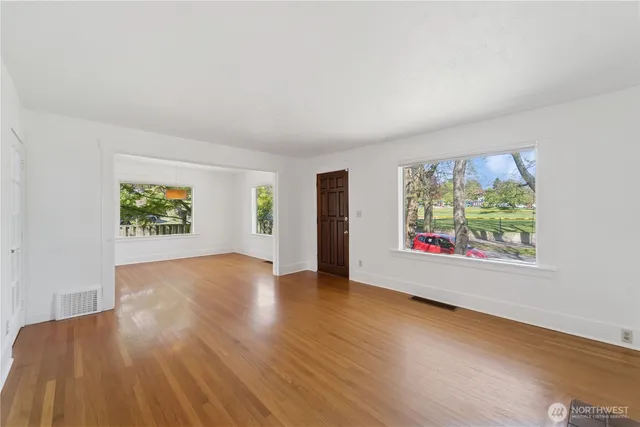 a view of an empty room with window and wooden floor