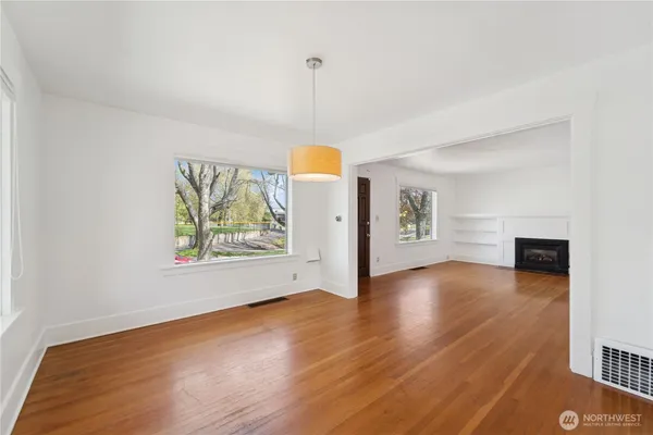a view of an empty room with window and wooden floor