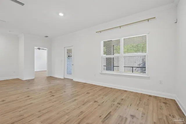 a view of an empty room with wooden floor and a window