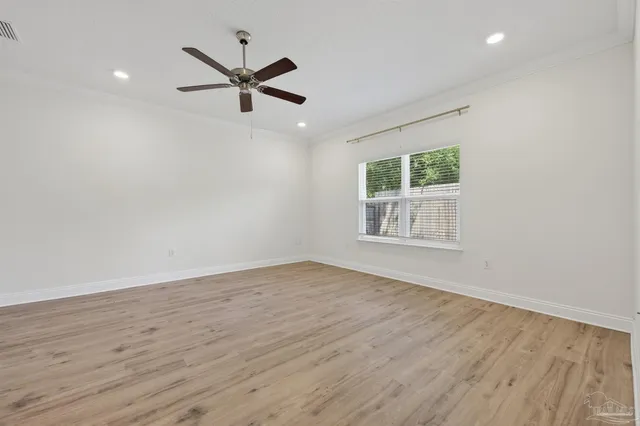 an empty room with wooden floor a ceiling fan and windows