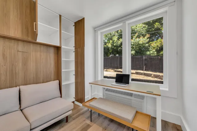 a living room with a bed furniture and a flat screen tv