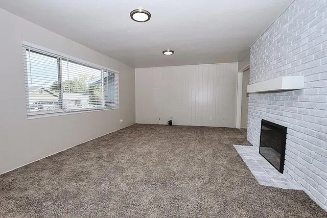 an empty room with windows and fireplace