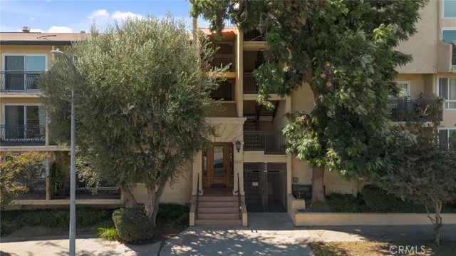 a view of a house with large tree and wooden fence
