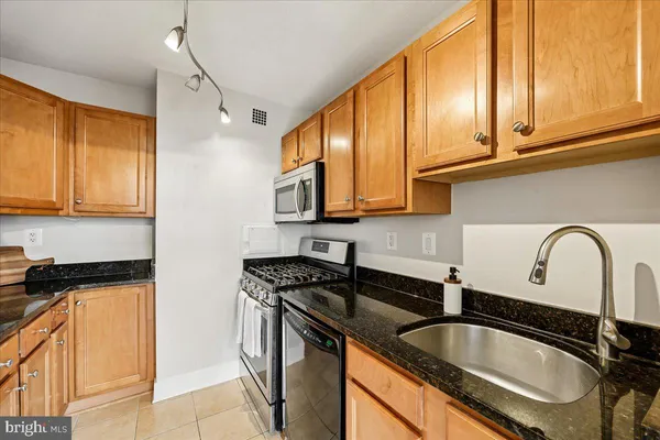 a kitchen with granite countertop a sink a stove and cabinets