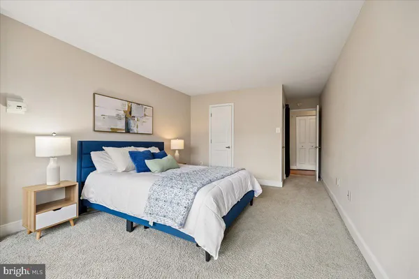a spacious bedroom with a bed and a lamp