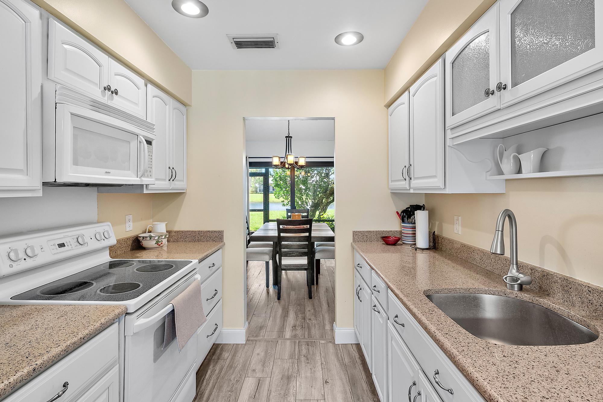 3733 Cape Pointe Circle Jupiter, FL 33477 - Photo 5 of 38 a kitchen with kitchen island granite countertop a sink a stove and cabinets