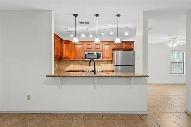 a view of a kitchen with stainless steel appliances granite countertop a sink and cabinets
