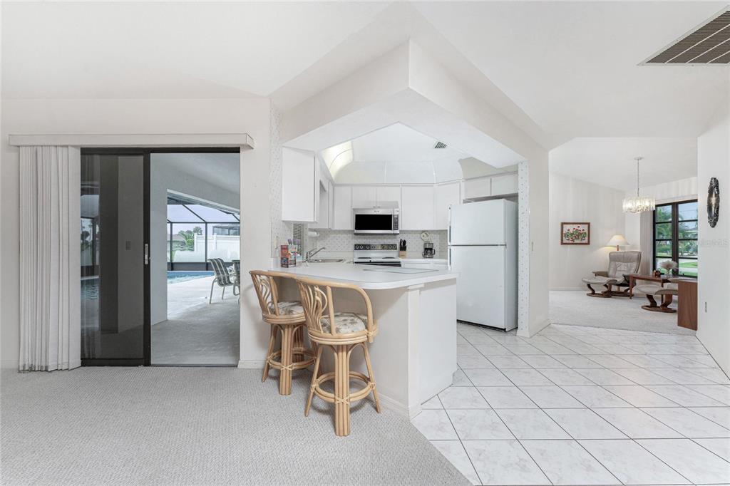 21 Bunker Lane Rotonda West, FL 33947 - Photo 19 of 51 a kitchen with kitchen island a refrigerator a stove a sink and chairs