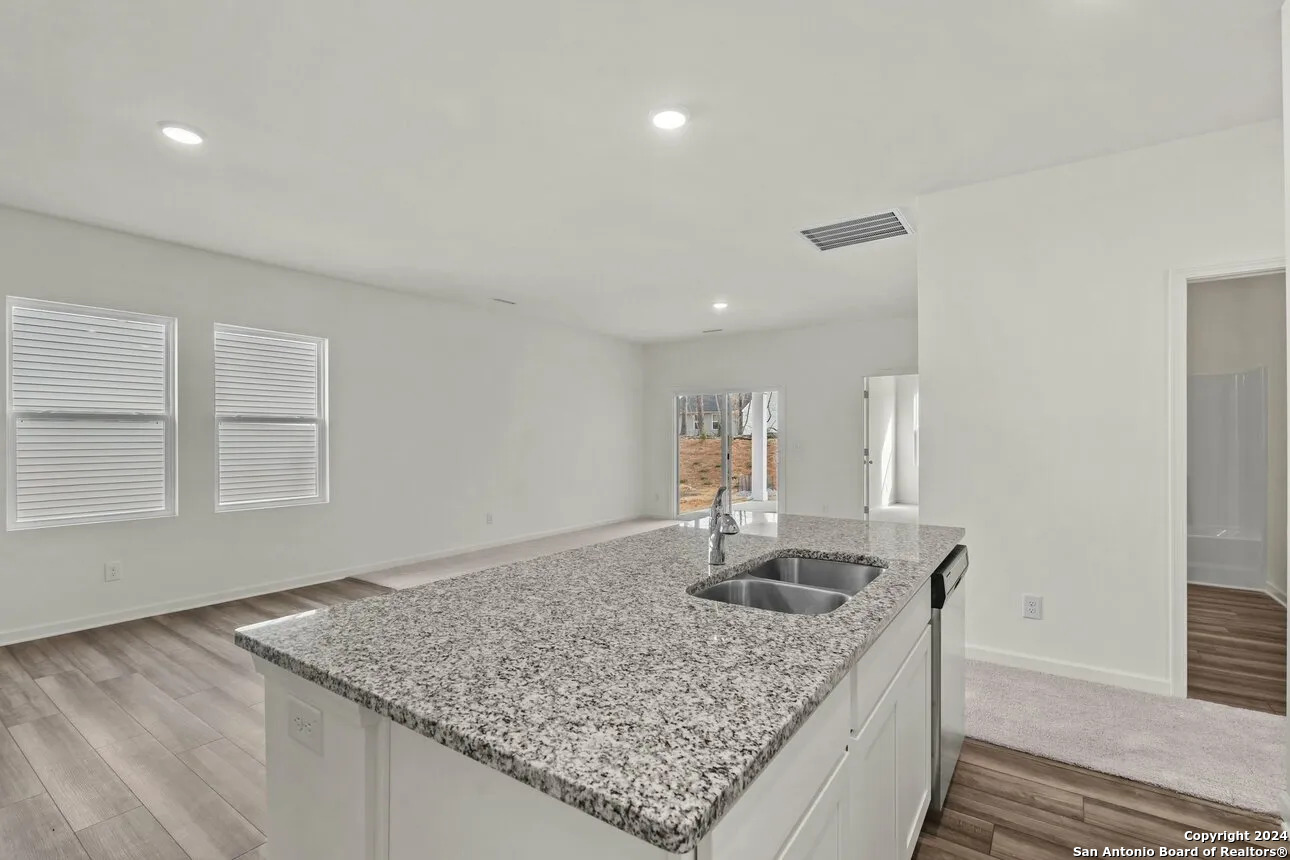 10507 Lesser Snow Adkins, TX 78101 - Photo 7 of 18 a kitchen with kitchen island granite countertop a sink window and refrigerator