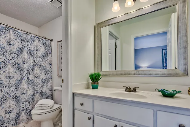 a bathroom with a granite countertop sink a toilet and a mirror