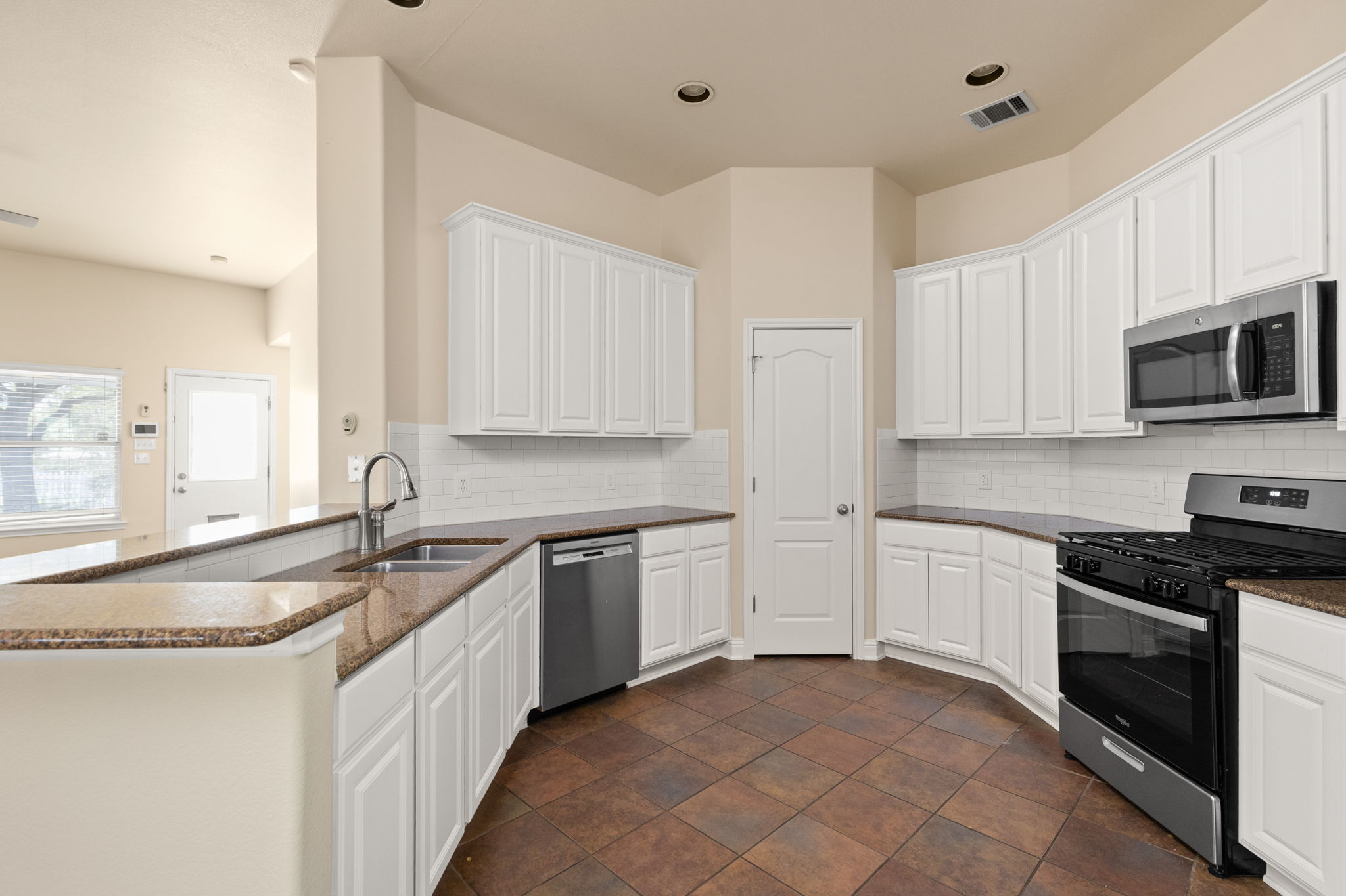 784 Sampson Kyle, TX 78640 - Photo 24 of 40 Ample cabinetry and stone countertops frame this well-appointed kitchen featuring durable tile flooring.