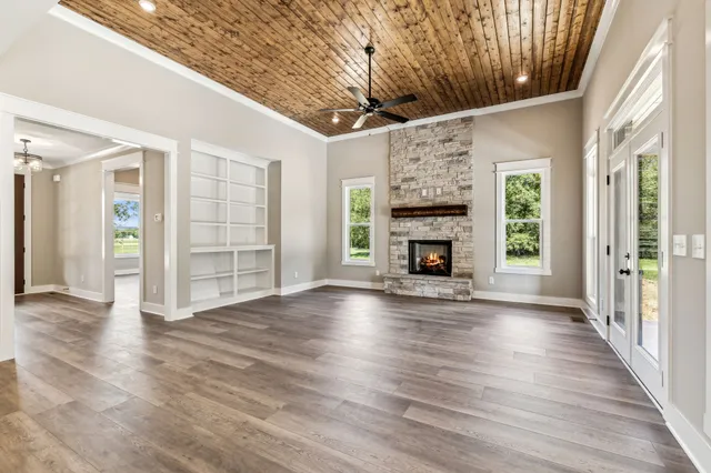 an empty room with wooden floor fireplace and windows
