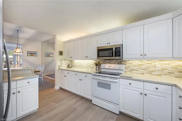 a kitchen with granite countertop white cabinets and stainless steel appliances