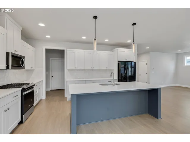 a kitchen with a sink a stove a refrigerator and white cabinets