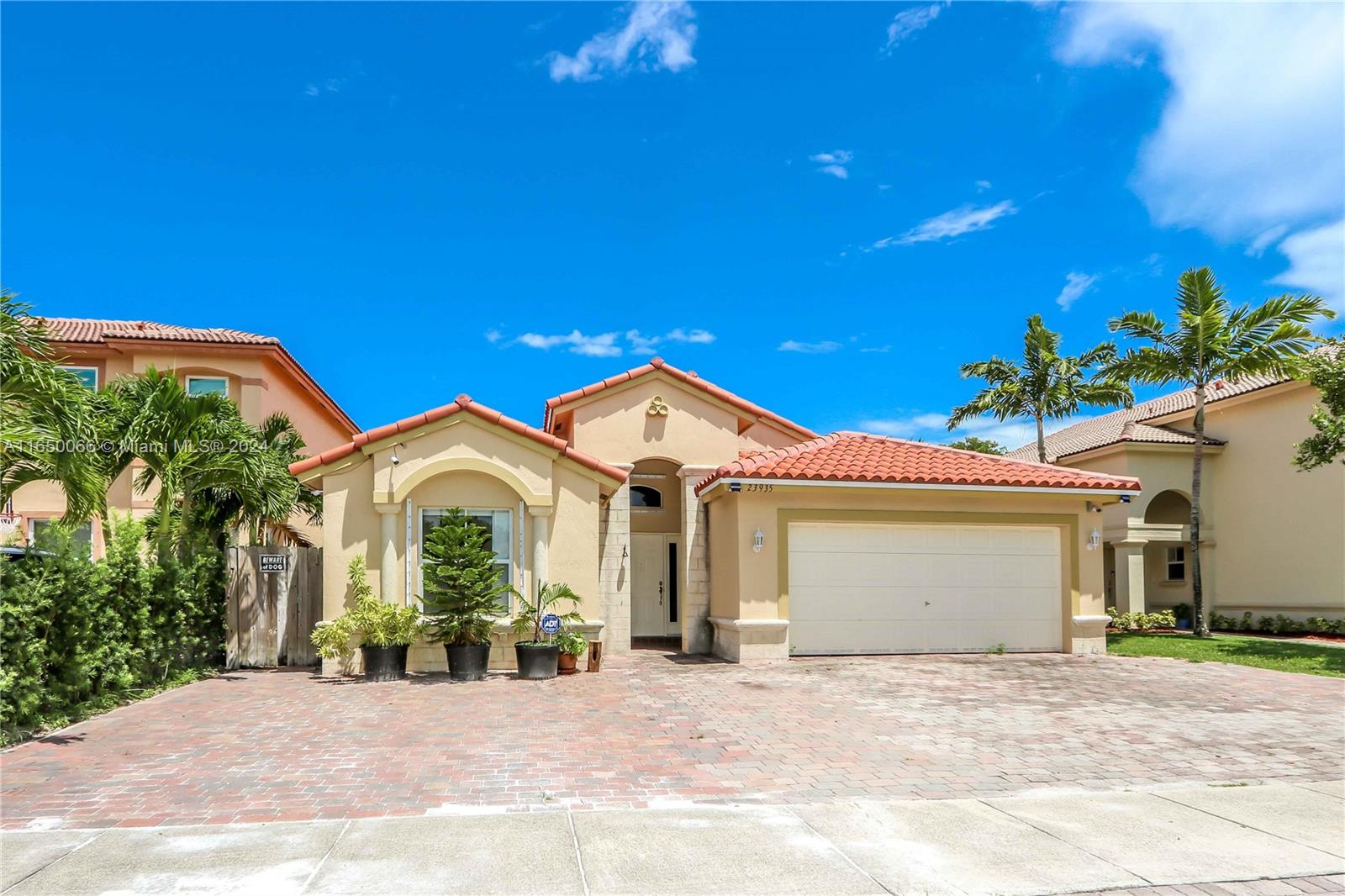 a front view of a house with a yard and potted plants
