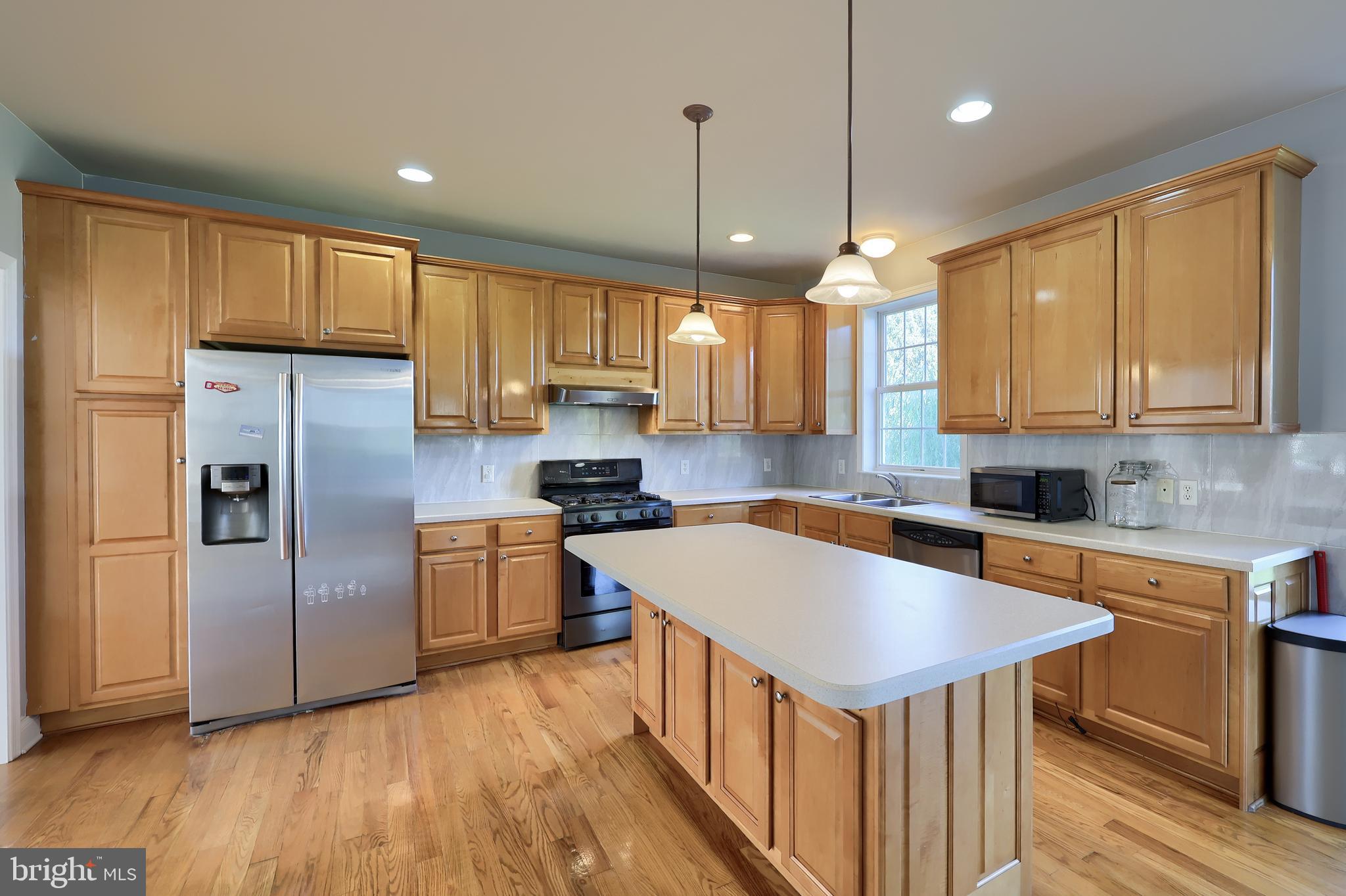 327 Squire Lane Lititz, PA 17543 - Photo 12 of 48 a kitchen with stainless steel appliances granite countertop a sink a stove a refrigerator and island with wooden floor