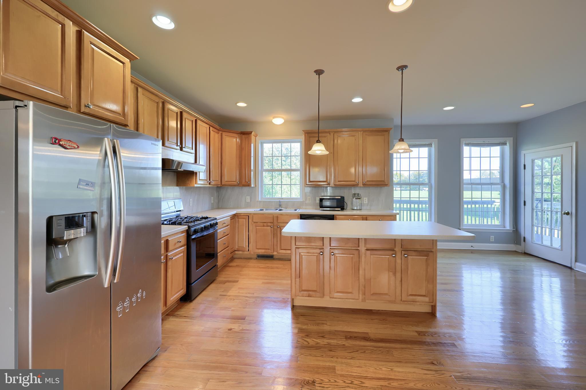 327 Squire Lane Lititz, PA 17543 - Photo 8 of 48 a large kitchen with stainless steel appliances granite countertop a refrigerator a sink dishwasher a oven and a large kitchen island with wooden floor