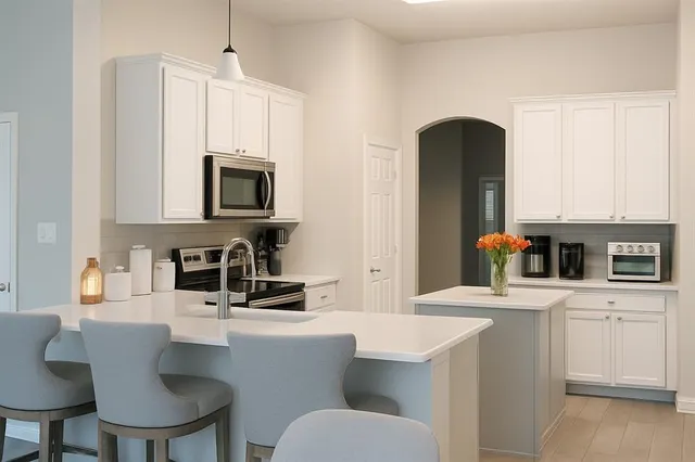 a kitchen with stainless steel appliances a white table chairs and a refrigerator
