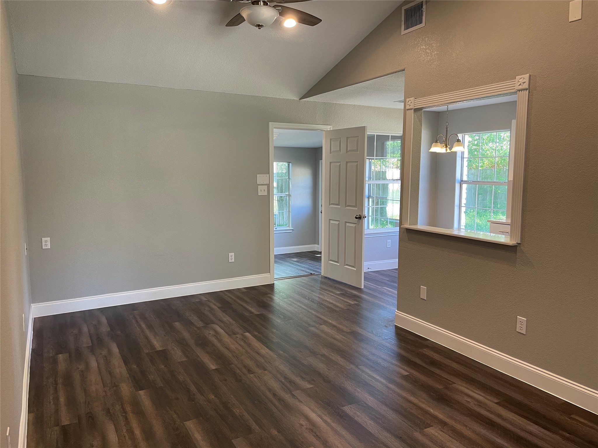 2004 Maple Street Georgetown, TX 78626 - Photo 14 of 31 Spacious interior room featuring wood-finish flooring, vaulted ceilings, a ceiling fan with integrated lighting, and a pass-through window with decorative trim