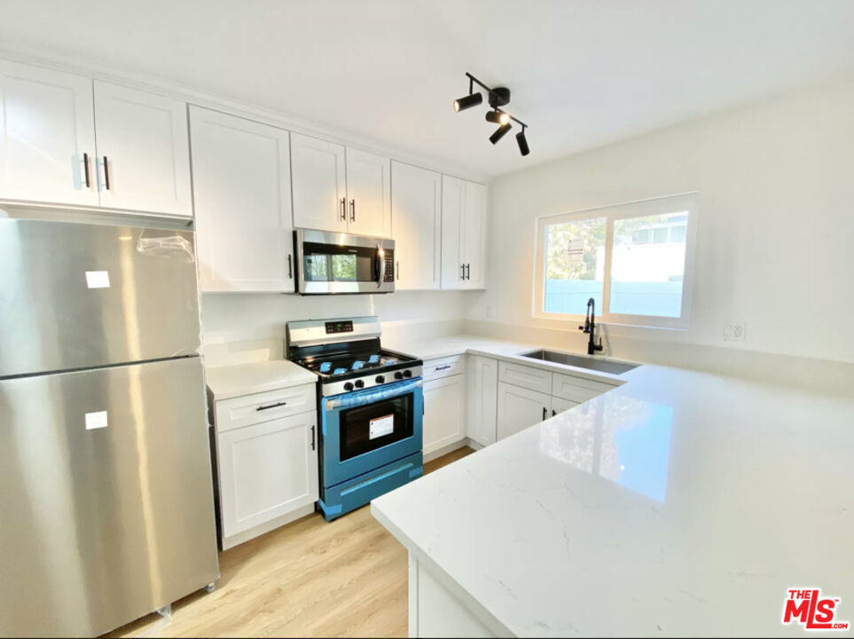 3824 Keystone Avenue, Unit 2 Culver City, CA 90232 - Photo 3 of 10 a kitchen with stainless steel appliances granite countertop a sink a stove a refrigerator a microwave a sink and cabinets