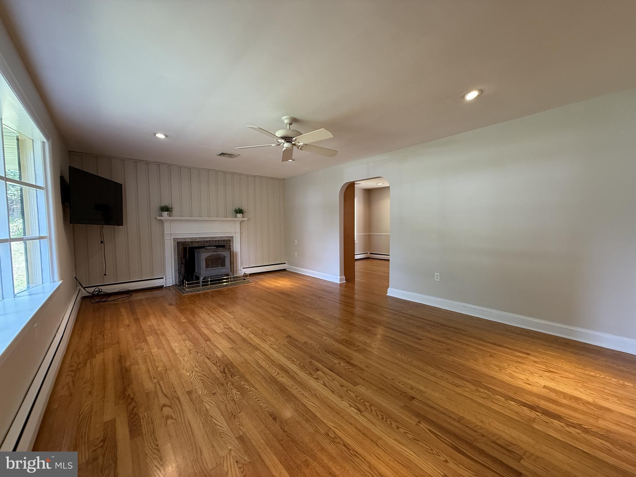 325 Greene Road Berwyn, PA 19312 - Photo 15 of 50 an empty room with wooden floor a fireplace and windows