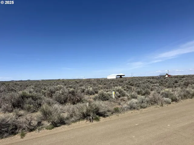 an aerial view of field with trees in background