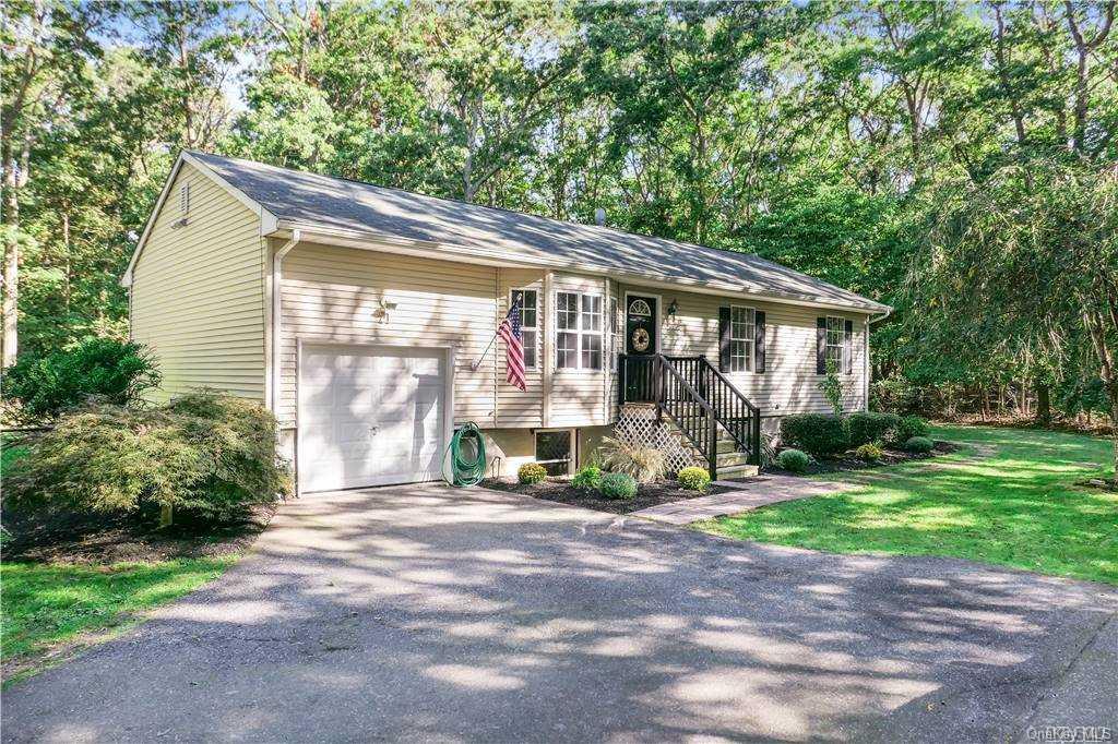 21 Pond Lane Ridge, NY 11961 - Photo 1 of 1 a porch with a table and chairs under an umbrella