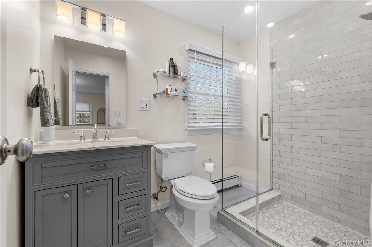 8 Heritage Court Cold Spring Harbor, NY 11724 - Photo 20 of 38 a bathroom with a granite countertop sink a toilet and shower