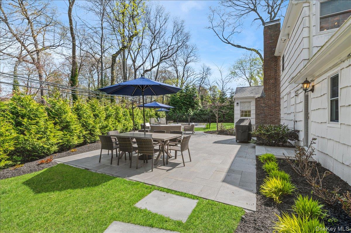 8 Heritage Court Cold Spring Harbor, NY 11724 - Photo 32 of 38 a view of a patio with table and chairs under an umbrella