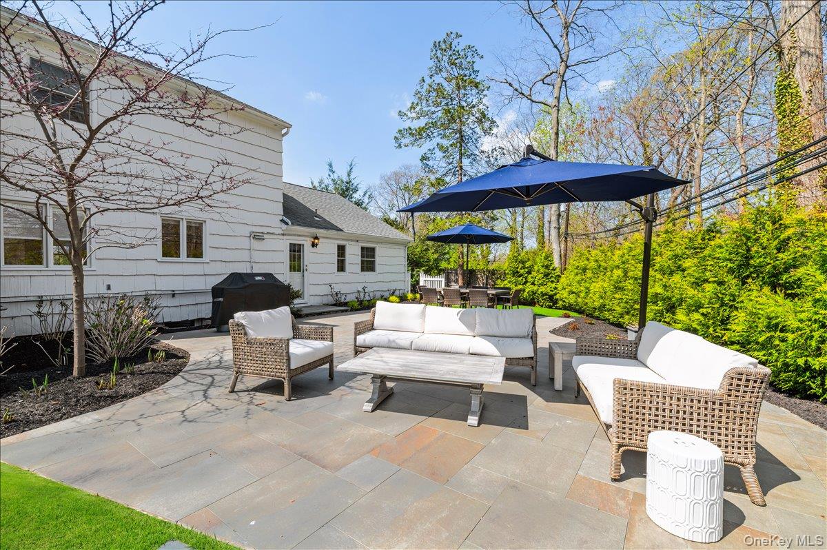 8 Heritage Court Cold Spring Harbor, NY 11724 - Photo 33 of 38 a view of a patio with a table and chairs under an umbrella
