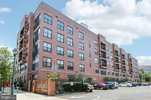 a front view of a building with lot of cars and trees