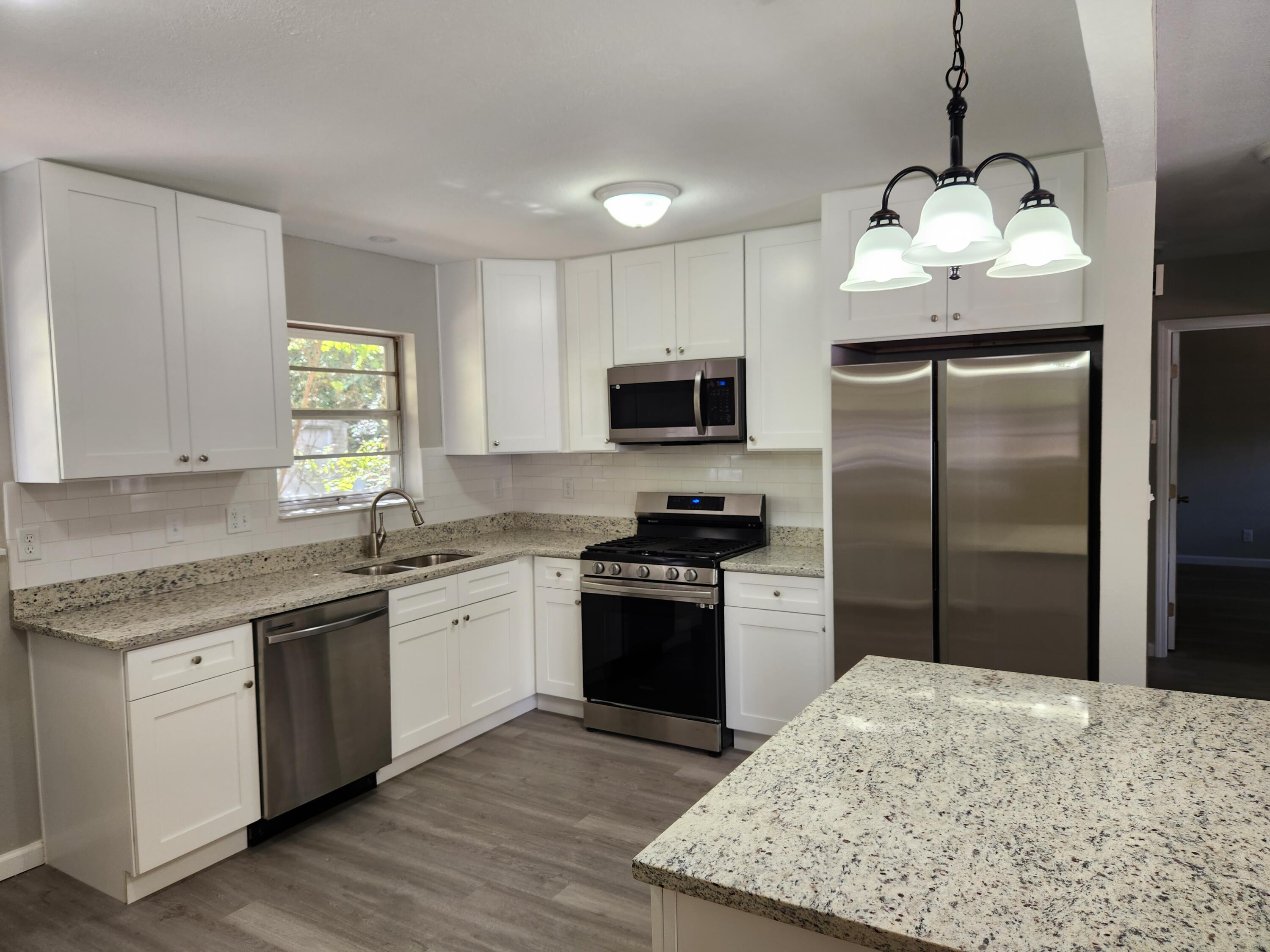 a kitchen with stainless steel appliances granite countertop a sink stove a refrigerator and a granite counter top