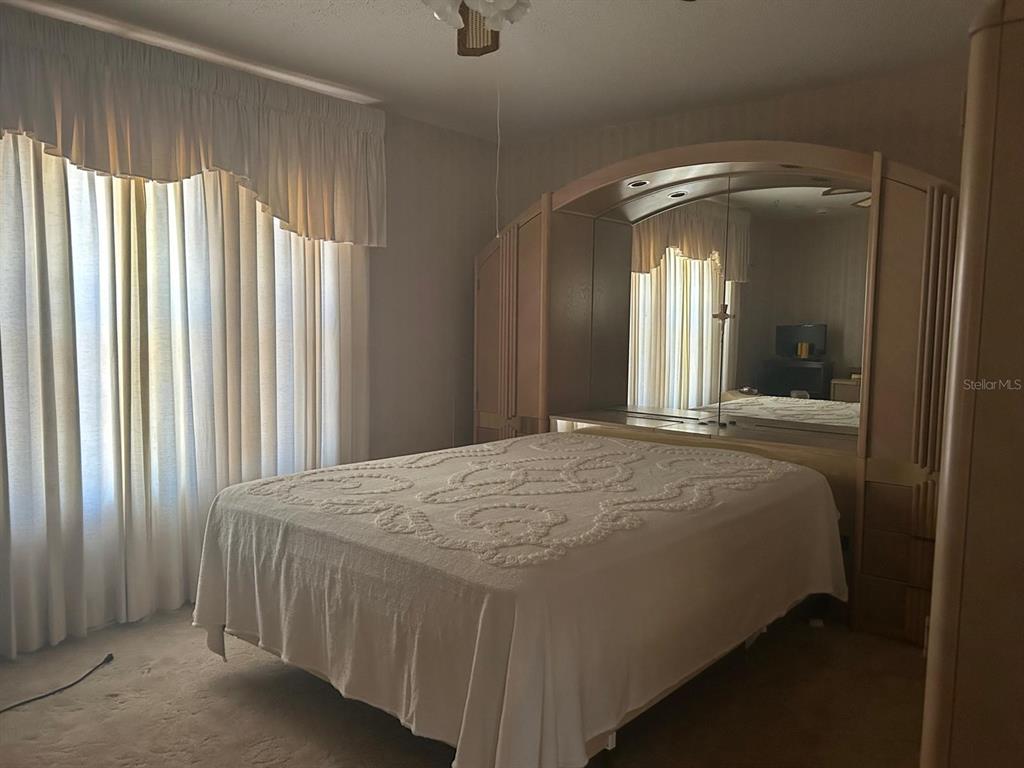 568 Silver Course Loop Ocala, FL 34472 - Photo 11 of 26 a bedroom with a bed and a large mirror