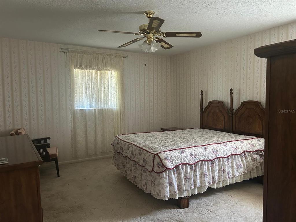 568 Silver Course Loop Ocala, FL 34472 - Photo 7 of 26 a bedroom with a bed and a chandelier