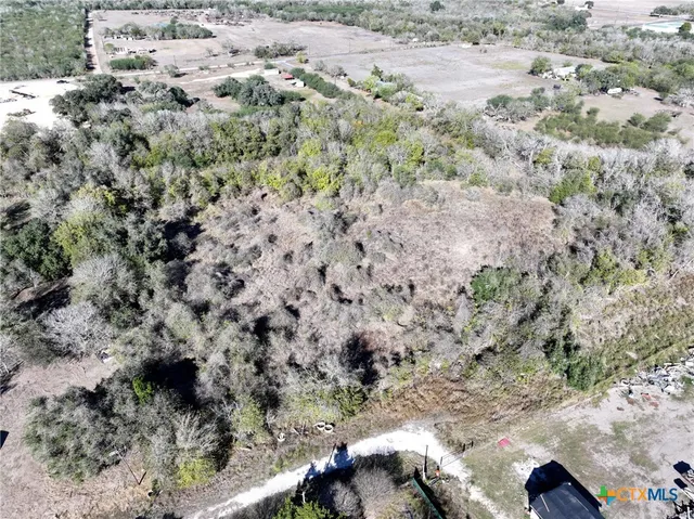 a view of a dry field with trees in the background