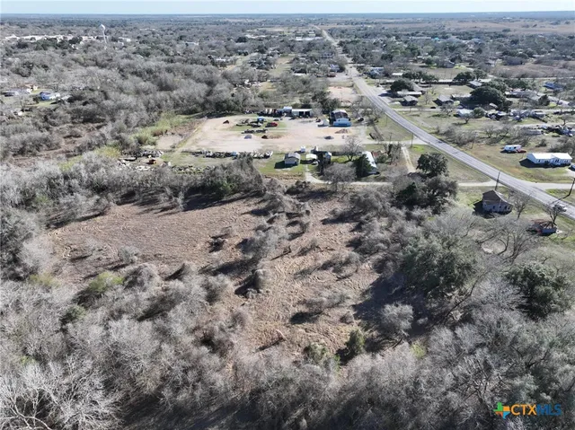 a view of dirt field with trees in the background