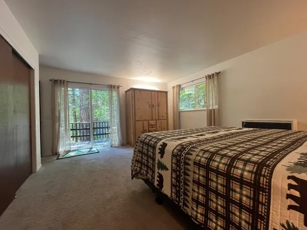 a bedroom with a balcony a bed and a dresser next to a window