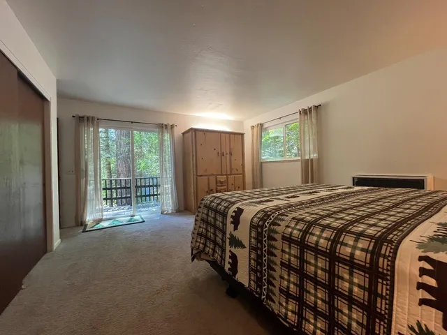 a bedroom with a balcony a bed and a dresser next to a window