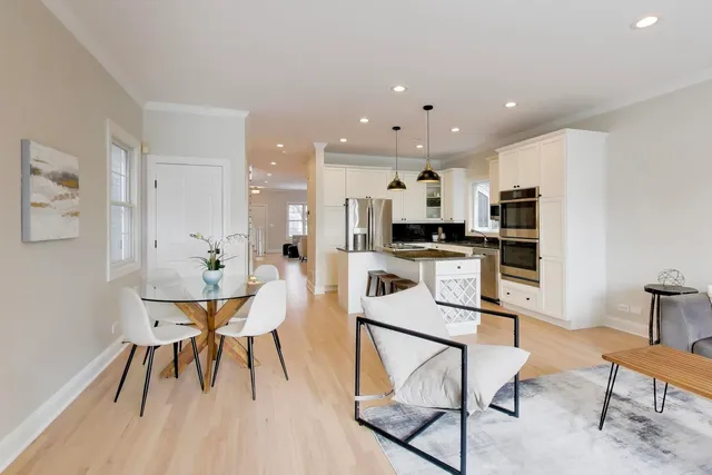 a kitchen with stainless steel appliances kitchen island granite countertop a dining table chairs and a refrigerator