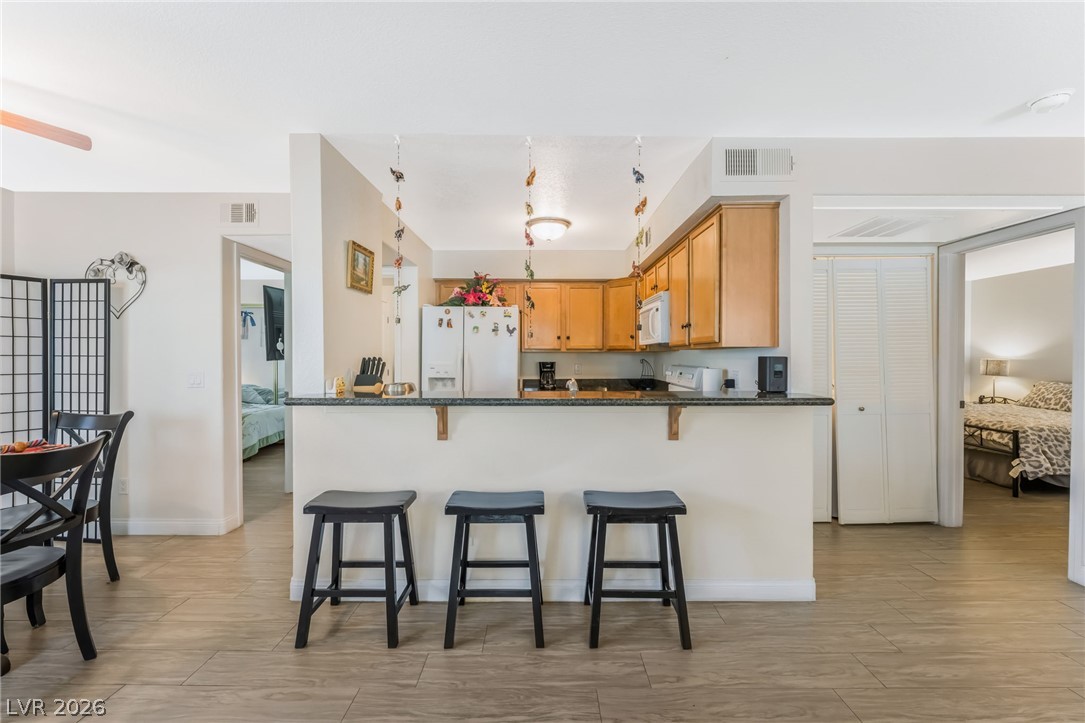 3145 East Flamingo Road, Unit 1092 Las Vegas, NV 89121 - Photo 5 of 33 A well-appointed kitchen featuring a breakfast bar with seating and wood cabinetry.